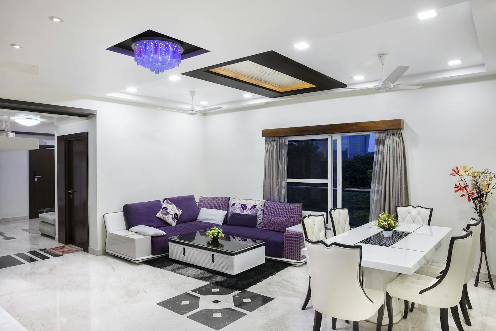 Elegant living room with modern decor, featuring a purple sofa and chic dining area.